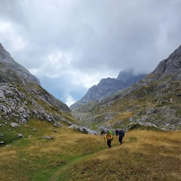 Mountain trail with hikers surrounded by alpine peaks and green valleys